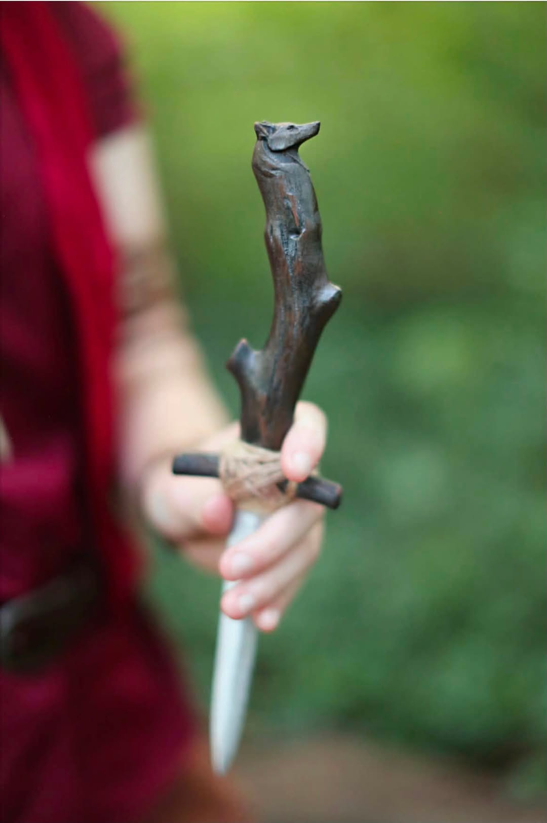 A hand carved dagger with an animal head pommel, showing the woodworking side of the shop.